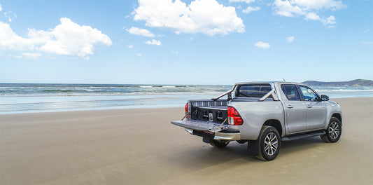 Silver ute with DECKED drawer system parked on open Australian beach